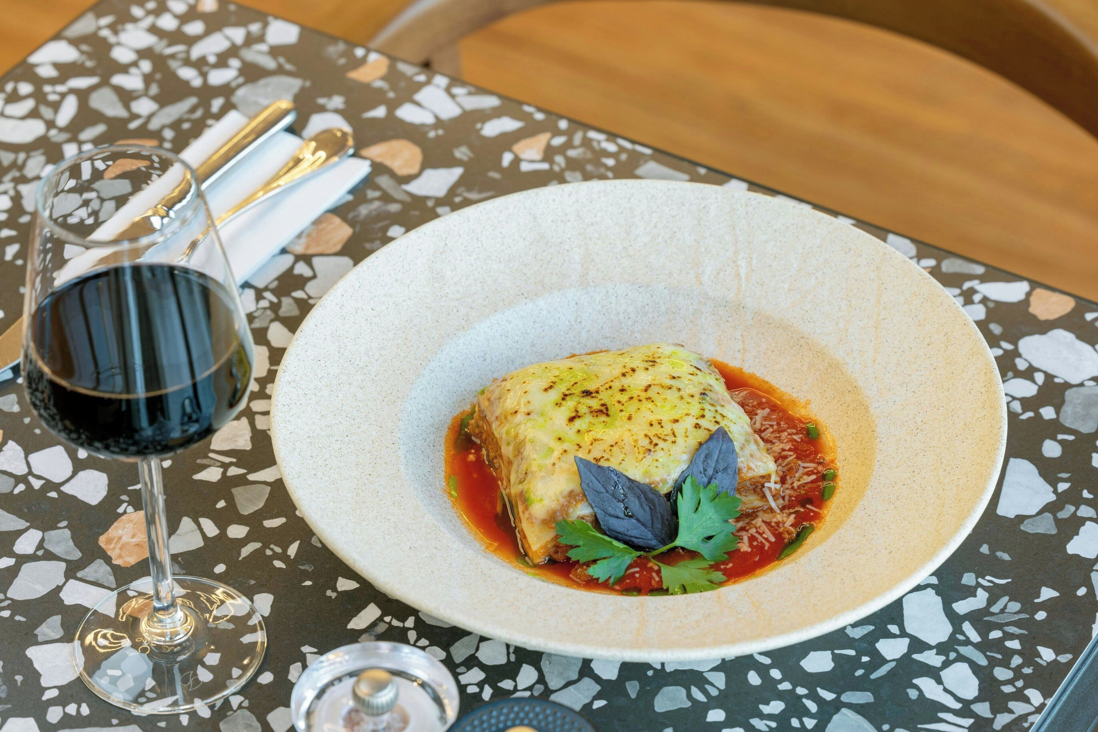 A plate of food with a glass of red wine on a table with a terrazzo surface.