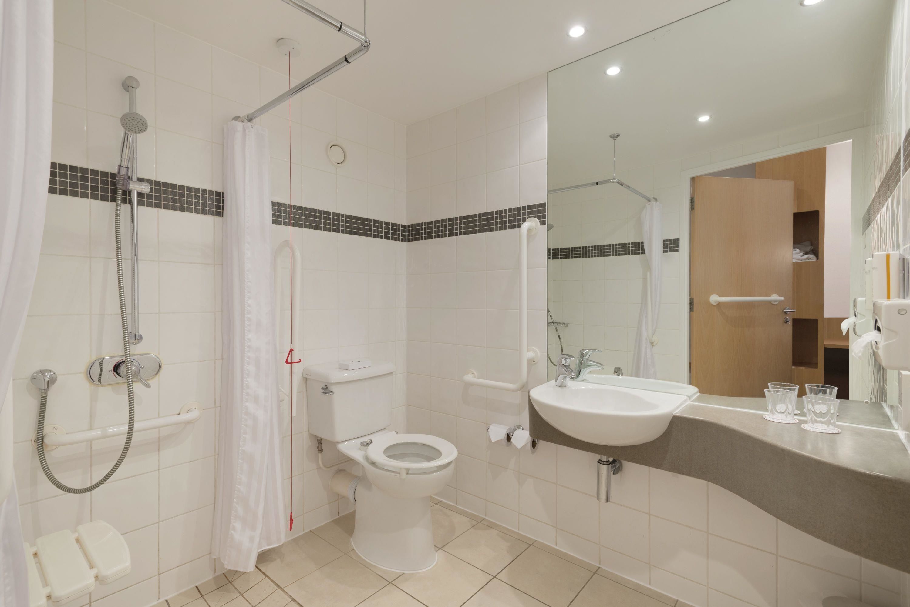 A modern bathroom with a shower, toilet, and sink.
