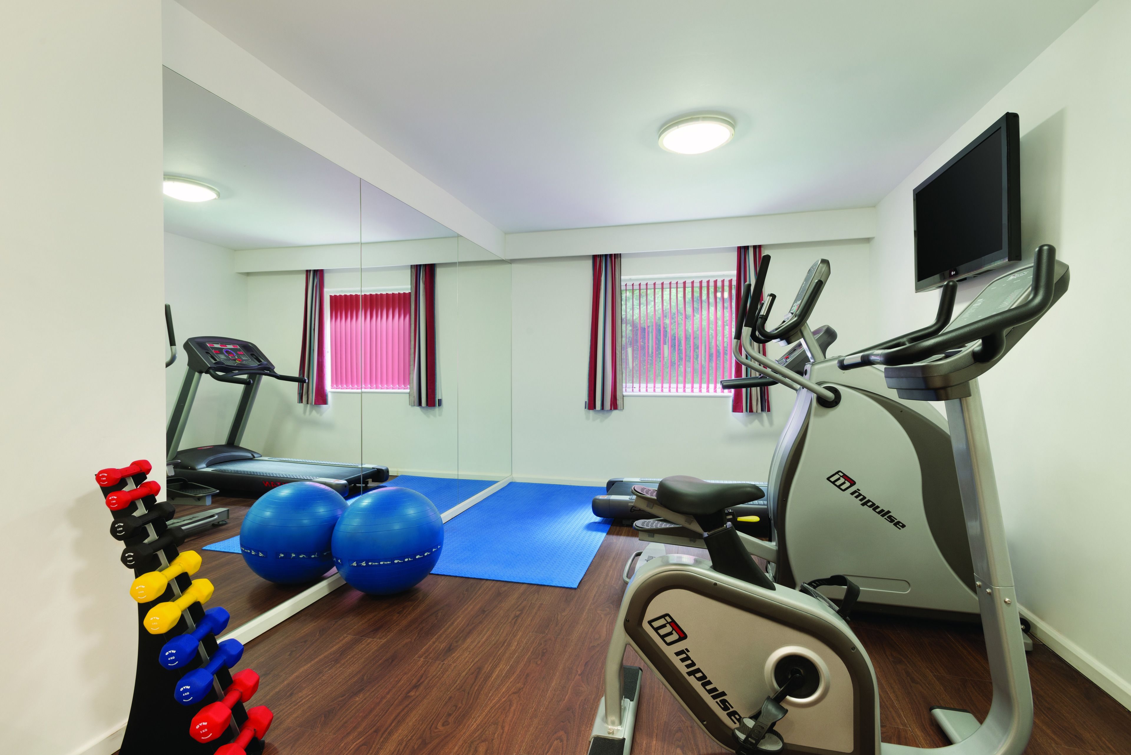 A gym with treadmills, an elliptical, exercise balls, and dumbbells.