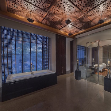A modern hotel lobby with a large window, a reception desk, and a glass partition.