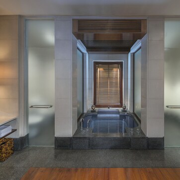 A modern bathroom with a large bathtub, two sinks, and a wooden floor.