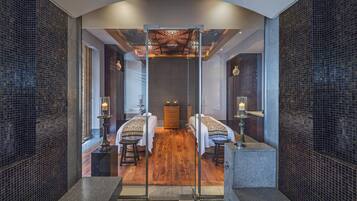 A modern hotel room with two beds, a wooden floor, and a glass partition.