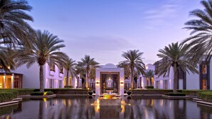 A luxurious hotel with a central fountain, palm trees, and modern architecture. - The Chedi Muscat (Muscat)