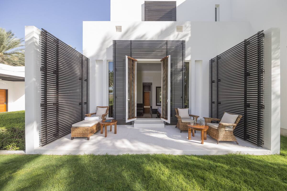 A modern outdoor patio with wicker furniture and a white exterior wall.