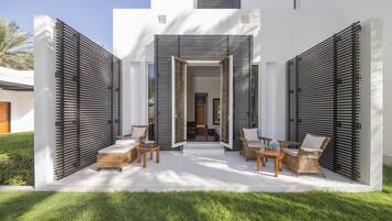A modern outdoor patio with wicker furniture and a white exterior wall.