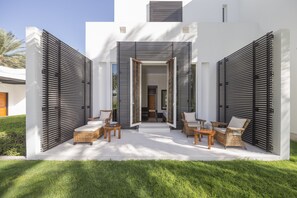 A modern outdoor patio with wicker furniture and a white exterior wall. - The Chedi Muscat (Muscat)