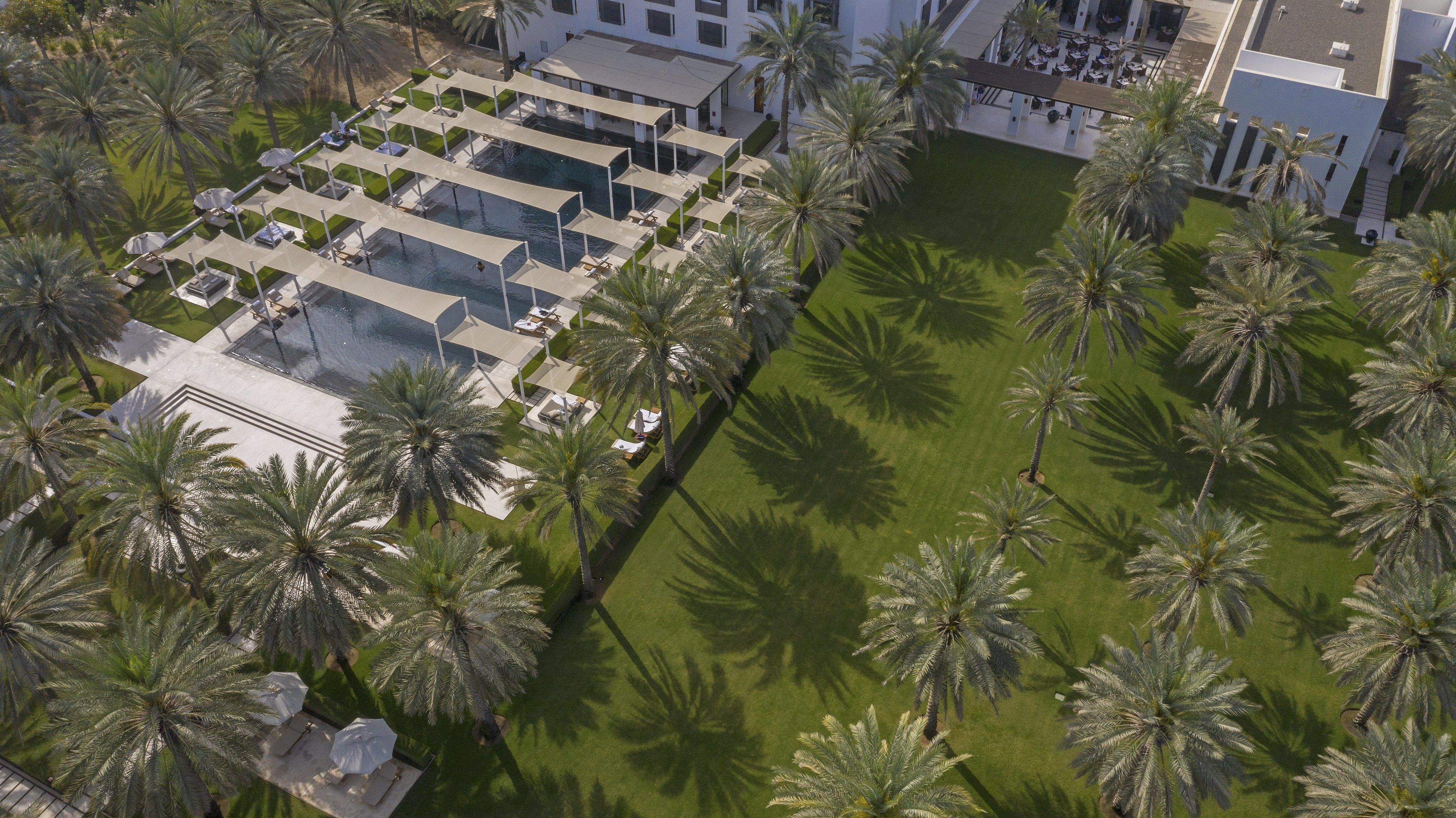Vista aérea de un resort con varias piscinas, palmeras y una estructura de edificio moderna.