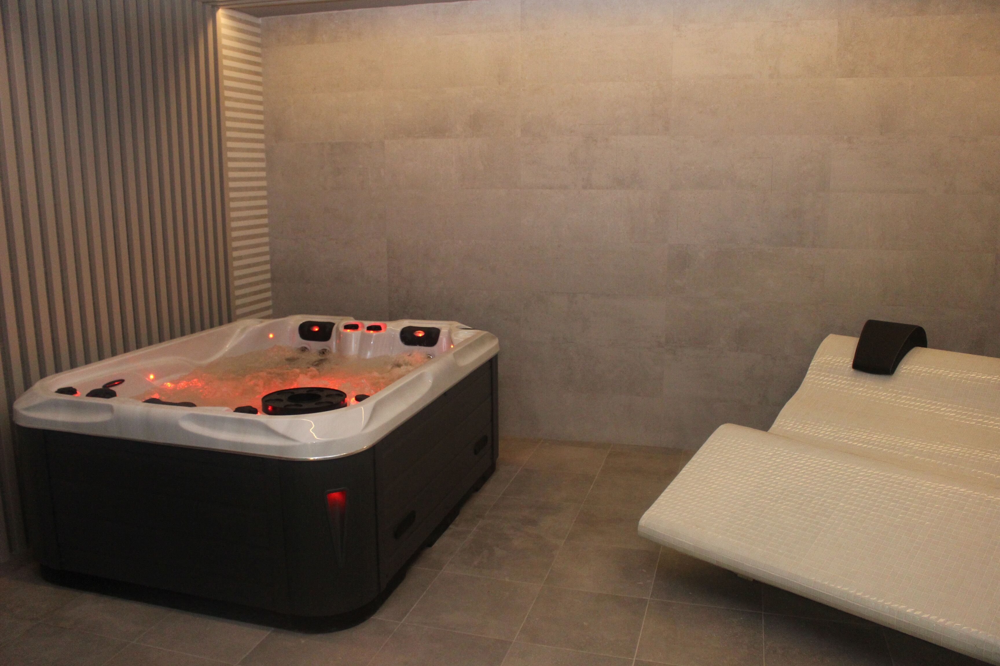Une salle de spa équipée d’un bain à remous et d’une table de massage.