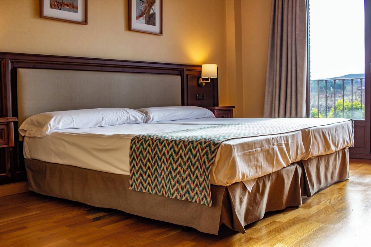 Une chambre d’hôtel avec un grand lit, une tête de lit en bois et une vue sur l’extérieur.