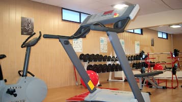 A gym with cardio equipment, weightlifting stations, and informational posters on the walls.