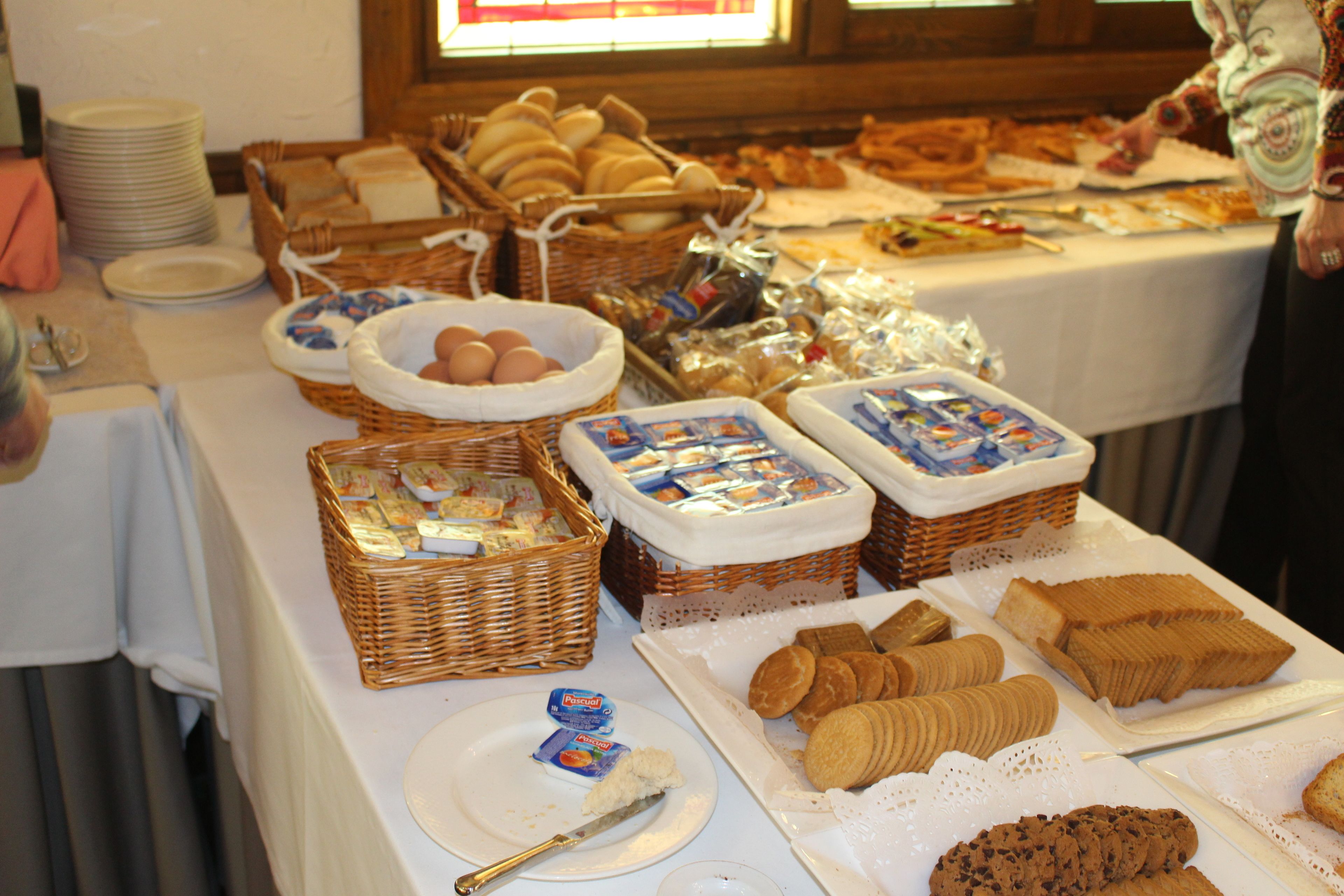 A buffet table with various food items including bread, pastries, and cookies.
