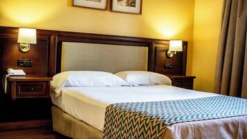 A hotel room with a large bed, two bedside tables, a nightstand, and a lamp.
