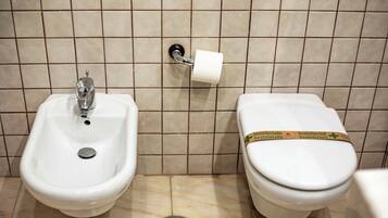 Un baño con bidé, inodoro y dispensador de toallas de papel.