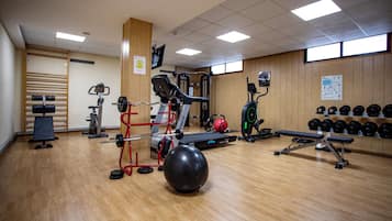 Un gimnasio con diverso equipo de ejercicio, incluyendo cinta de correr, banco de pesas y pesas sueltas.
