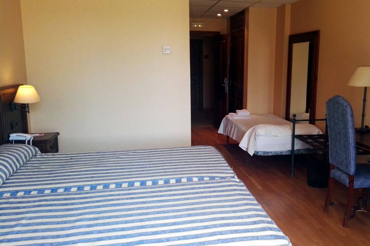 Une chambre d’hôtel avec deux lits, un bureau, une chaise, une lampe et un tableau au mur.