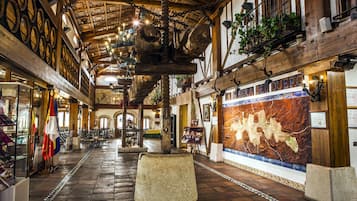 Un bâtiment historique avec des poutres en bois, un banc en pierre et une fresque représentant une carte.