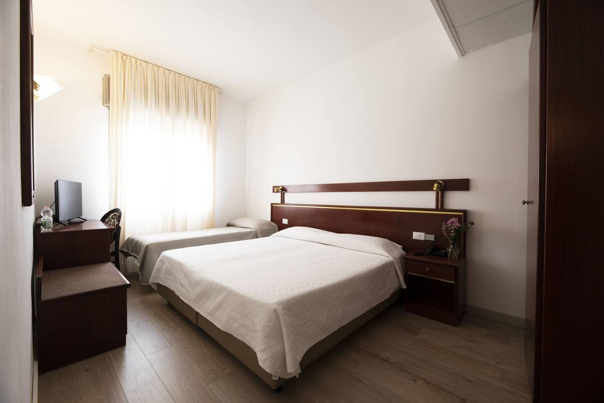 Ein Hotelzimmer mit zwei Betten, einem Schreibtisch und einem Sessel.