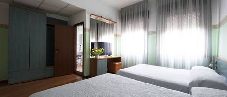 Una habitación de hotel con dos camas, un escritorio con espejo y un armario.