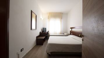 A hotel room with two beds, a desk, a chair, a TV, and a window with curtains.