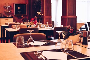 A restaurant with tables set for dining, including cutlery and glassware.