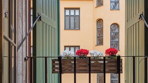 An open gate leading to a courtyard with a yellow building, green shutters, and a wooden bench with flowers. - Unique Hotel (Stockholm)