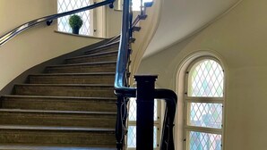 A curved staircase with a metal railing, leading to a landing with a view of the outside. - Unique Hotel (Stockholm)