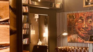 A cozy lounge area with a leather sofa, a small table, and a bookshelf filled with books. - Unique Hotel (Stockholm)