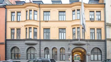 A multi-story building with a yellow facade, large windows, and a flagpole.
