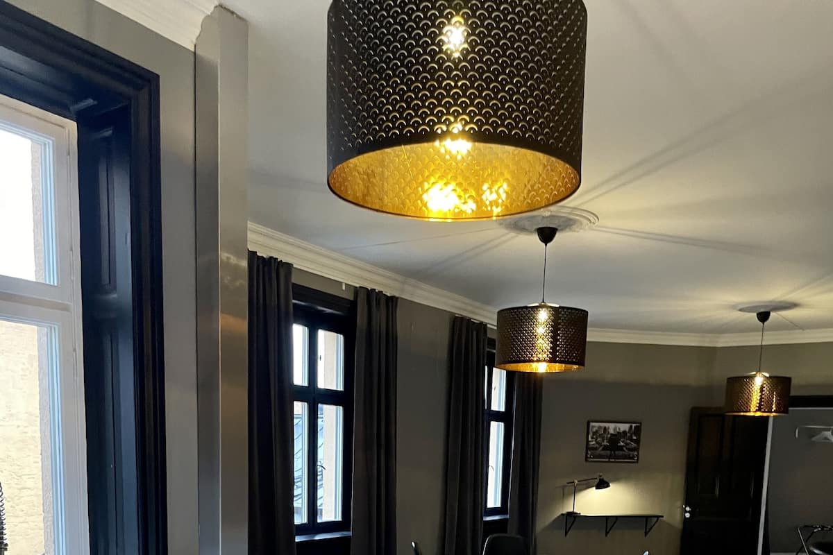 A modern kitchen with a large island, dark curtains, and pendant lighting.
