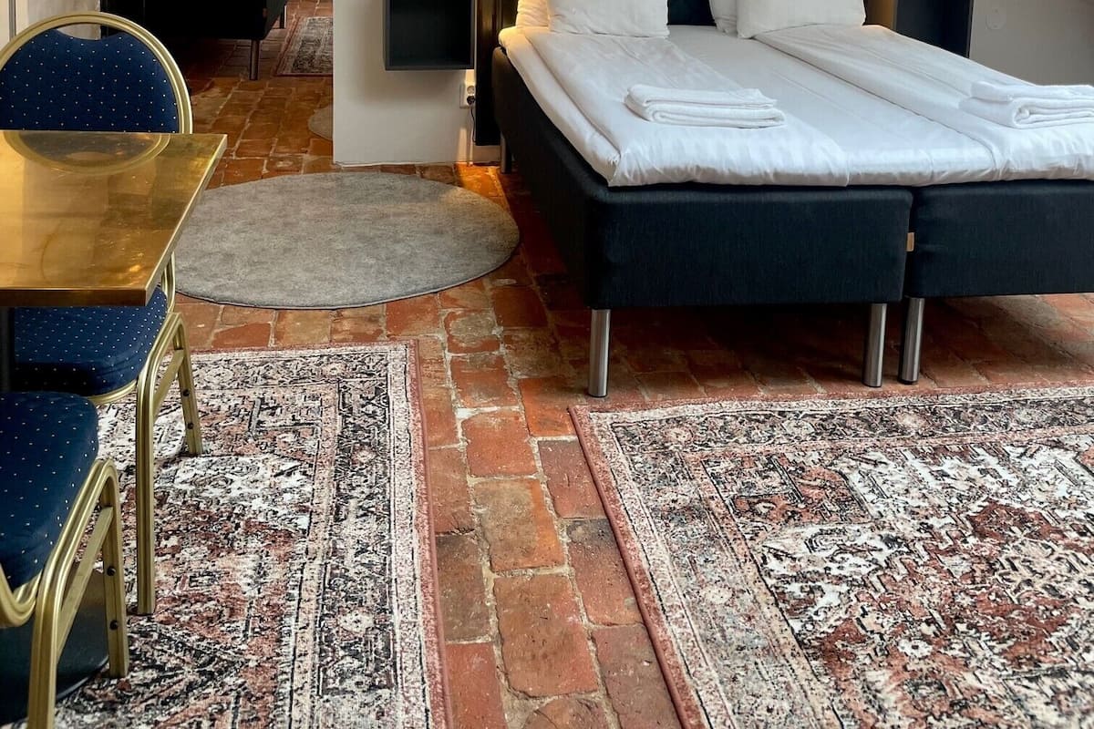 A bedroom with a bed, bedside tables, a chair, and a rug.