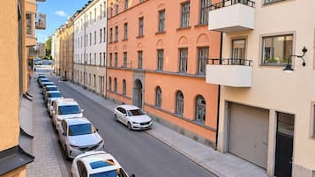A row of parked cars along a street lined with multi-story buildings.