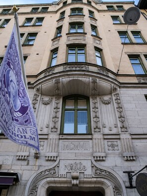 A building facade with a classical architectural style, featuring a central arched window and decorative stonework.