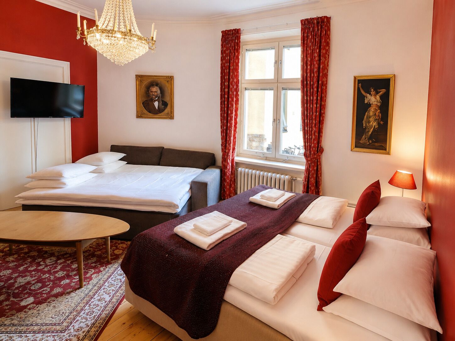 Una habitación de hotel con cama, escritorio, televisor y candelabro.