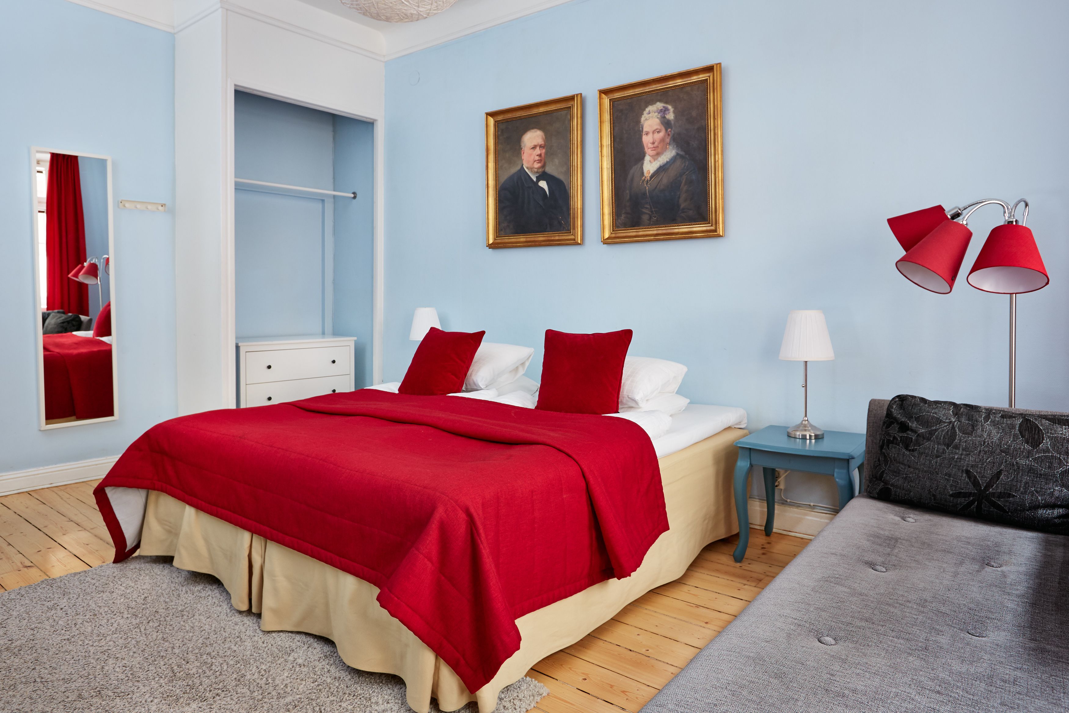 Un dormitorio con cama, mesita de noche, cómoda, espejo y dos cuadros en la pared.