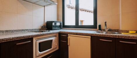 Eine Küche mit Mikrowelle, Toaster, Spüle und einem Fenster mit Blick auf ein Gebäude.