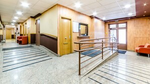 A hotel lobby with a marble floor, wooden walls, a reception desk, and a staircase with a metal railing. - JCH Congreso (Salamanca)