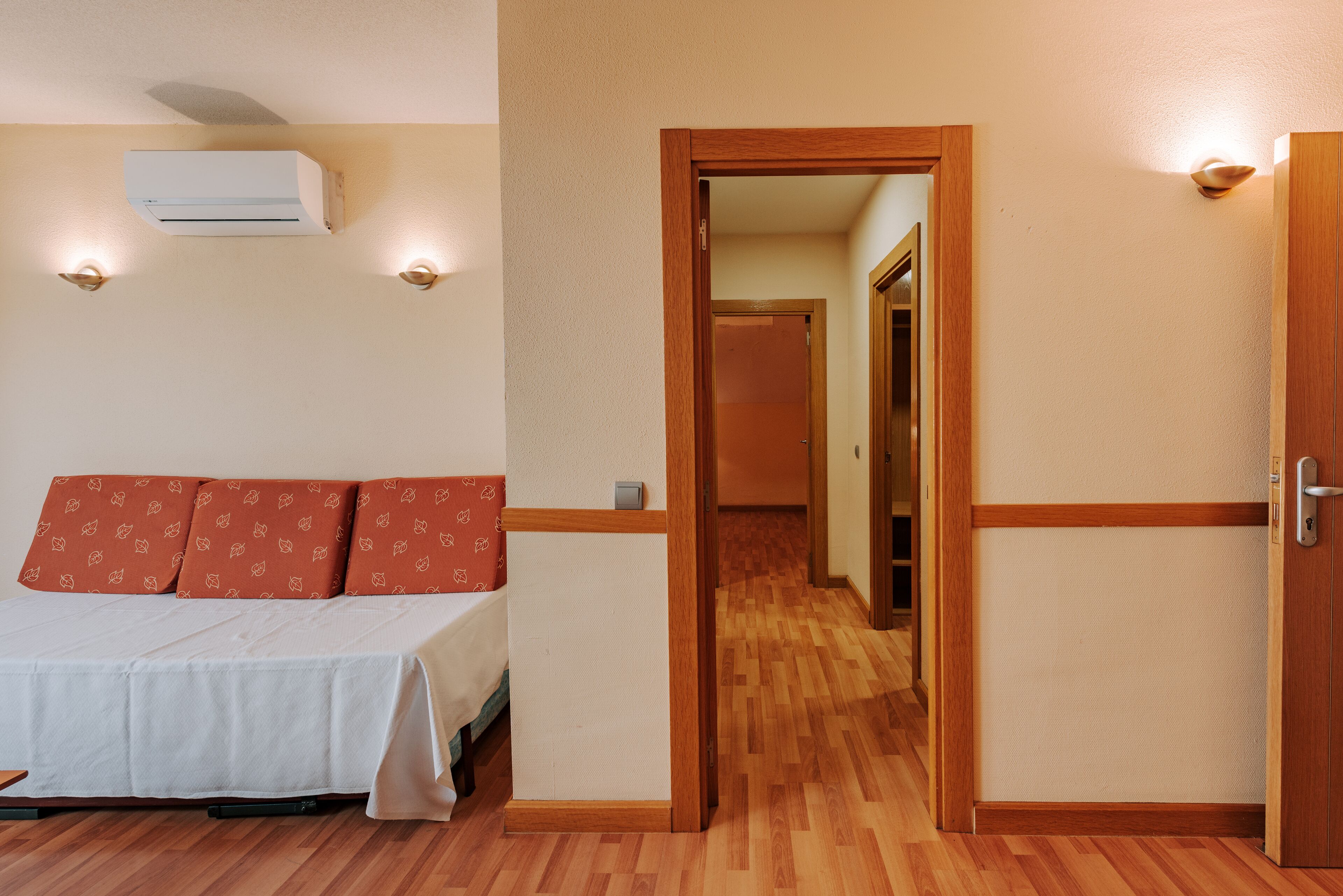A hotel room with a bed, a wardrobe, and a hallway.