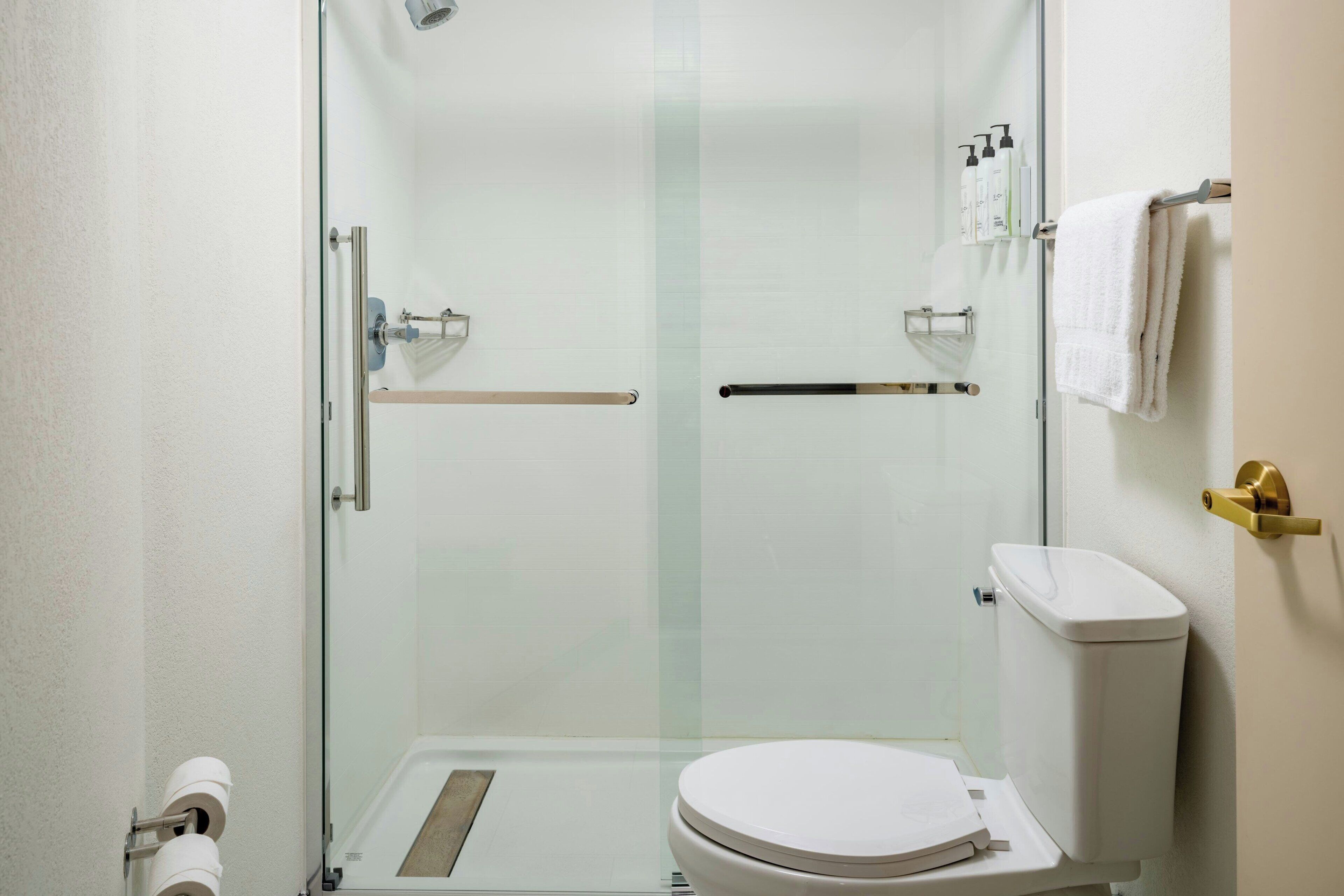 A modern bathroom with a glass-enclosed shower, a toilet, and a towel rack.