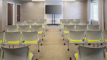 A conference room with rows of chairs, a large screen, and a carpeted floor.