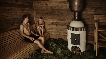 A sauna room with wooden benches and a central steam generator.