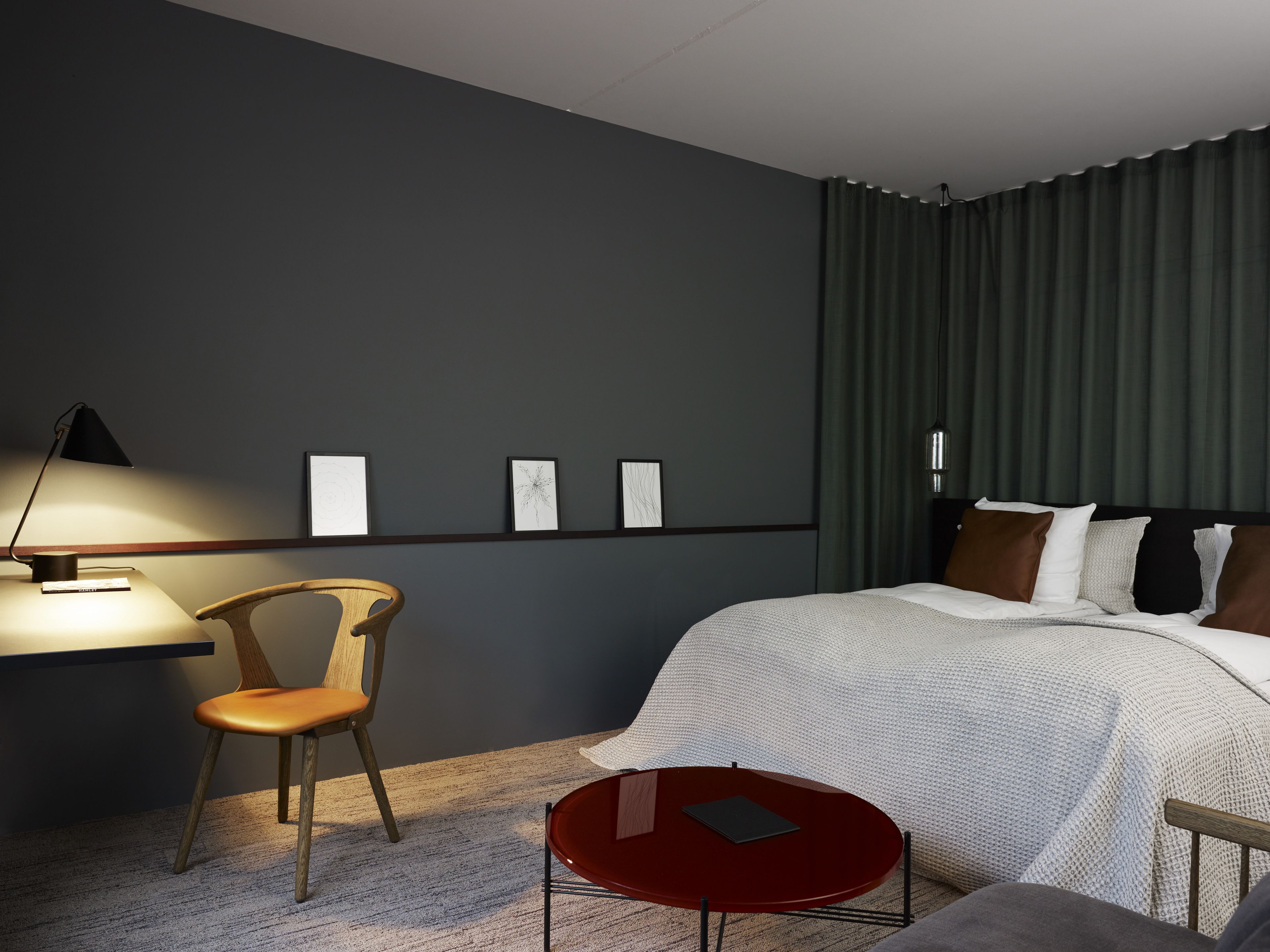 Una habitación de hotel moderna con una cama, un escritorio, una silla y una mesita.