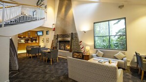 Un vaste espace de vie doté d’une cheminée, de sièges confortables, d’un bar et d’un escalier menant à un niveau supérieur.