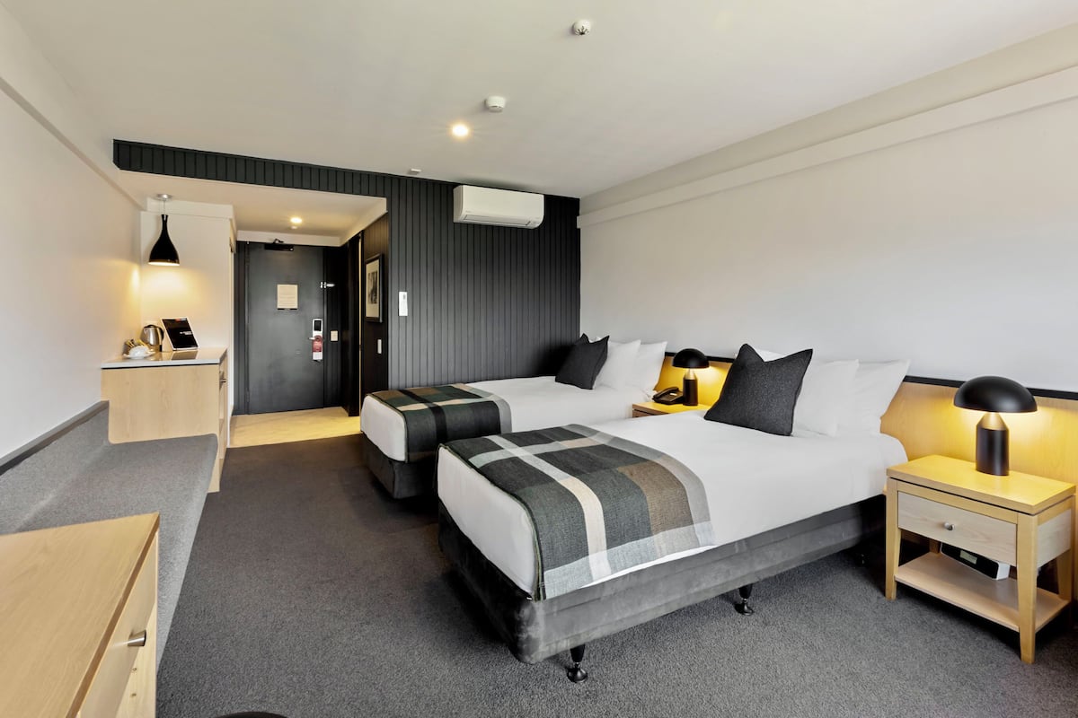 A modern hotel room with a large bed, two bedside tables, a desk, and a chair.