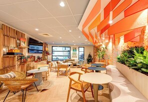 A modern cafe with wooden furniture, a Christmas tree, and large windows. - B&B HOME Rueil-Malmaison Gare (Rueil-Malmaison)