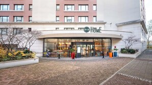 A hotel entrance with a glass facade, outdoor seating area, and a sign reading "B&B HOME". - B&B HOME Rueil-Malmaison Gare (Rueil-Malmaison)