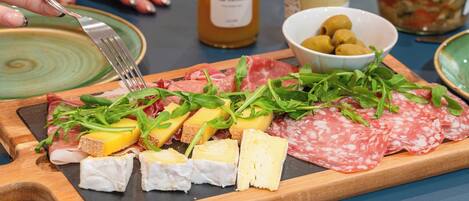 A charcuterie board with various meats, cheeses, and greens on a wooden board.