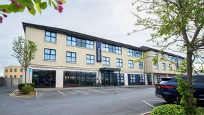 A Travelodge hotel with a modern facade, large windows, and a parking lot. - Travelodge Galway (Galway)