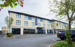 Un hotel Travelodge con una fachada moderna, amplias ventanas y un estacionamiento.