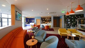 A hotel lobby with seating areas, a reception desk, and a bar. - Travelodge Galway (Galway)