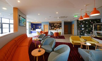 Un vestíbulo de hotel con zonas de estar, una recepción y un bar.